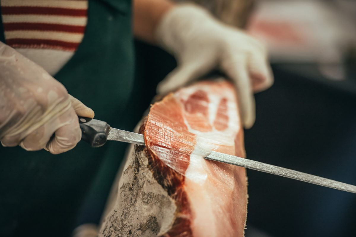 Slicing of italian dry-cured ham prosciutto. Toned image. Selective focus point